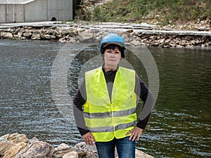 Woman worker in a helmet against the backdrop of hydroelectric turbines