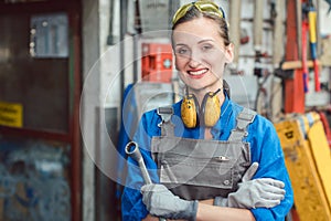 Woman worker in her metal workshop posing with tools