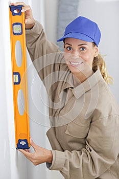 woman worker leaning spirit level on wall