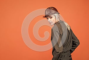 woman worker in protective helmet and boilersuit on orange background, copy space, 1 may