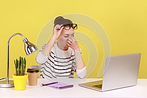 Woman worker rubbing tired of laptop work eyes, putting off glasses, sitting workplace, overworking.