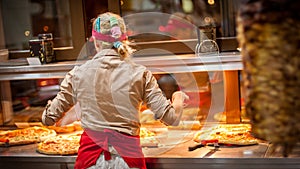 Woman worker selling pizza in fast food restaurant. Rear view