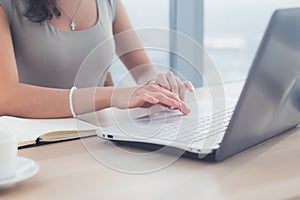 Woman working as copywriter at home. Close-up picture of female hands on pc keyboard in light office.