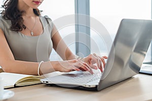 Woman working as copywriter at home. Close-up picture of female hands on pc keyboard in light office. photo