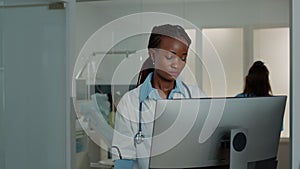 Woman working as doctor with stethoscope using computer