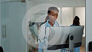 Woman working as doctor with stethoscope using computer