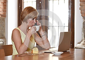 Woman working busy at coffee shop with laptop computer talking on mobile phone photo