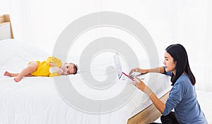 Woman is working busy on laptop computer and tablet at home while her  baby is sleeping