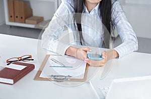 Woman working on celphone, sitting at the desk