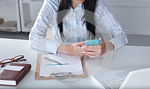 Woman working on celphone, sitting at the desk