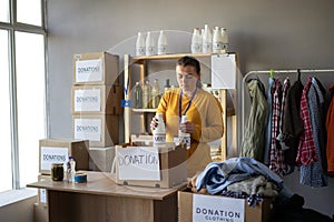 Woman working in charitable foundation. Volunteer packing donation box. Female volunteer sort donations during food