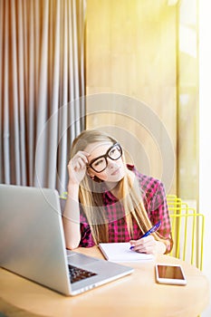 Woman working on a computer at a cafe. Tired face of woman.