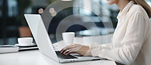 Woman working on computer in modern office, close up. Woman hands typing on keyboard of laptop, online shopping detail