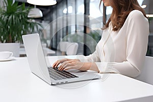 Woman working on computer in modern office, close up. Woman hands typing on keyboard of laptop, online shopping detail