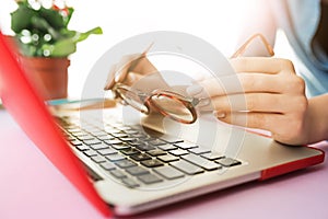 Woman working on computer in office and holding glasses