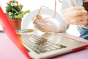 Woman working on computer in office and holding glasses