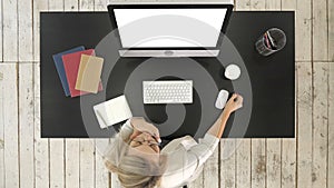 Woman working at computer in office tired drinking coffee. White Display.