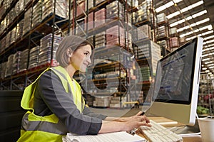 Woman working at computer in on-site office of a warehouse photo