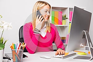 Woman working on computer and talking on the phone