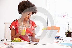 Woman Working In Design Studio Having Lunch At Desk