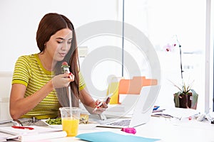 Woman Working In Design Studio Having Lunch At Desk