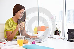 Woman Working In Design Studio Having Lunch At Desk