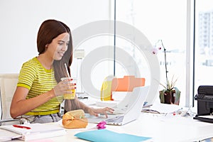 Woman Working In Design Studio Having Lunch At Desk