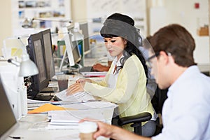 Woman Working At Desk In Busy Creative Office