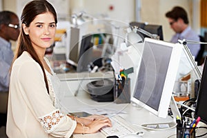 Woman Working At Desk In Busy Creative Office