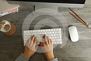 Woman working on desktop computer on gray wooden table