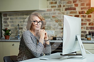 A woman working on a desktop computer with her employees at a video conference