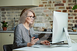 A woman working on a desktop computer with her employees at a video conference