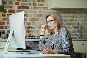 A woman working on a desktop computer with her employees at a video conference