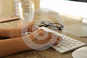 Woman working on desktop computer on wooden table