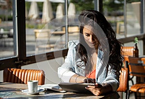 Woman working with a digital tablet while relaxing sitting in a coffee shop