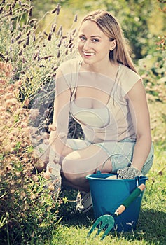 Woman working in garden using horticultural instruments on summer day