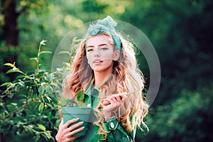 Woman working in green beautiful garden. Woman holding flower pot.