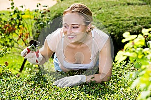 Woman working with green bush using horticultural tools