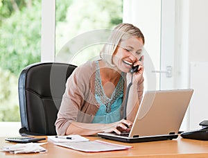 Woman working on her computer while she is phoning