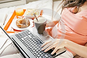 Woman working with her laptop computer and having breakfast