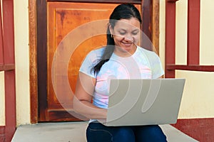Woman working with her laptop outside her home