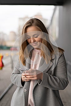 Woman working on her phone outdoors. Cold autumn weather