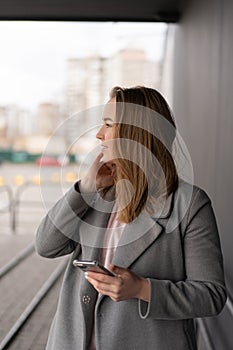 Woman working on her phone outdoors. Cold autumn weather