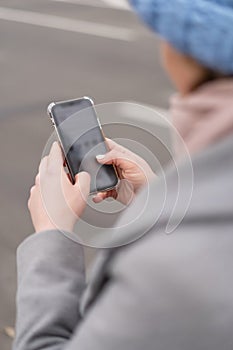 Woman working on her phone outdoors. Cold autumn weather