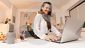 Woman working on her small business using laptop in home kitchen
