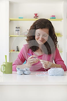 Woman working at her textile studio and creating baby bootees