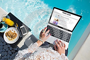 Woman working on her travel blog by the pool