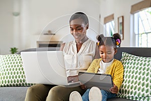 Woman working from home while her daughter using digital tablet