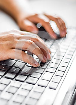 Woman working at home office hand on keyboard close up on wooden table