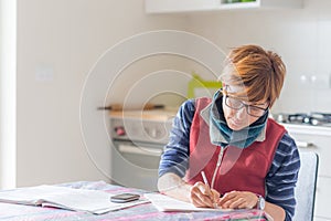 Woman working at home, reading and handwriting documents